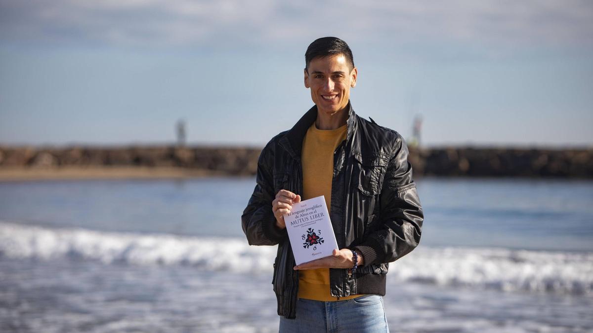 Juanma Marta, con su libro, en la playa del Port de Sagunt.