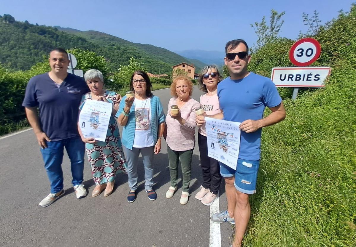 Por la izquierda, Pablo Sánchez, Nardi Iglesias, María Luisa Fidalgo, Geli Crespo, Consuelo Noval y Daniel Fernández, con carteles del certamen del quesu de Urbiés, que cumple 30 años.  | D. M.