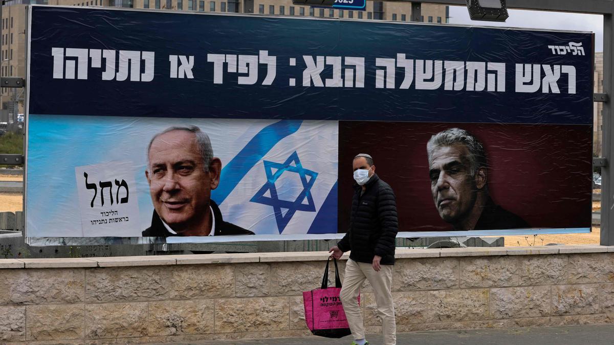 Un israelí camina frente a los carteles electorales del primer ministro, Binyamin Netanyahu, y uno de sus oponentes, Yair Lapid, líder del partido Hay Futuro.