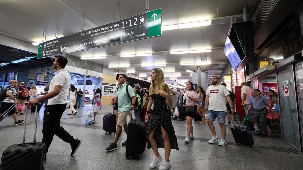 Un grupo de personas con maletas camina por uno de los pasillos de la estación de Atocha-Almudena Grandes con motivo de la operación salida de inicios de agosto, en Madrid (España).