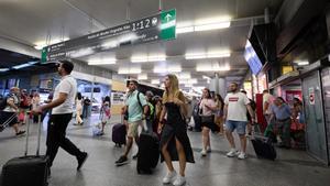 Un grupo de personas con maletas camina por uno de los pasillos de la estación de Atocha-Almudena Grandes con motivo de la operación salida de inicios de agosto, en Madrid (España).