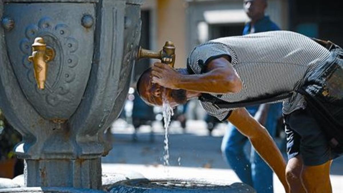 Un joven bebe agua en una fuente pública de Barcelona.