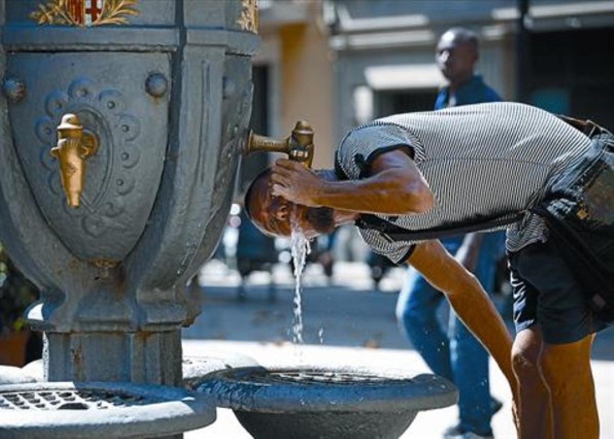 Un joven bebe agua en una fuente pública de Barcelona.