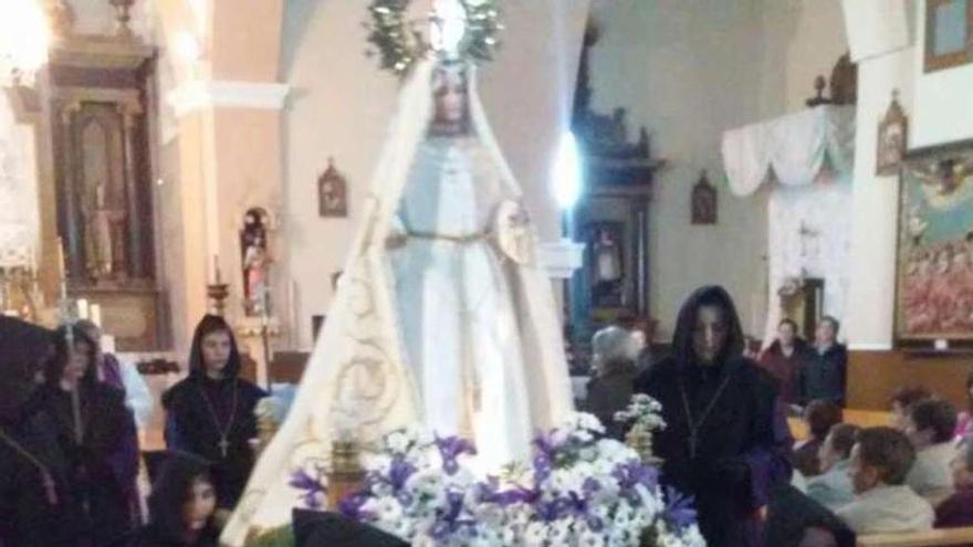 Cofrades de Manganeses de la Lampreana sacan de rodillas a la Virgen del Rosario. A la derecha, más hermanos arrodillados.