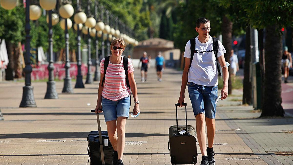 Dos turistas recién llegados caminan con maletas por el Paseo de la Victoria.