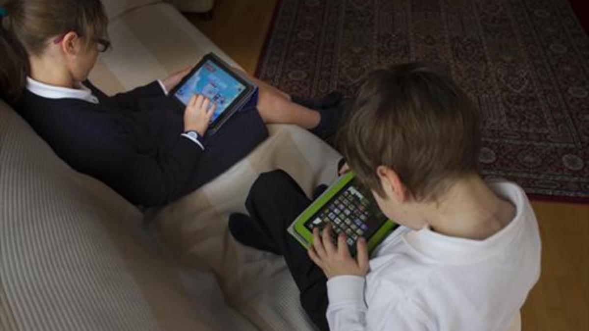 Dos niños juegan con tabletas electrónicas.