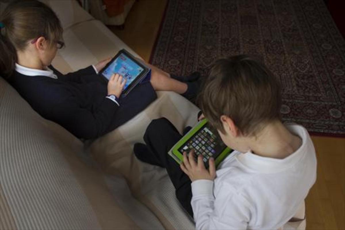 Dos niños juegan con tabletas electrónicas.