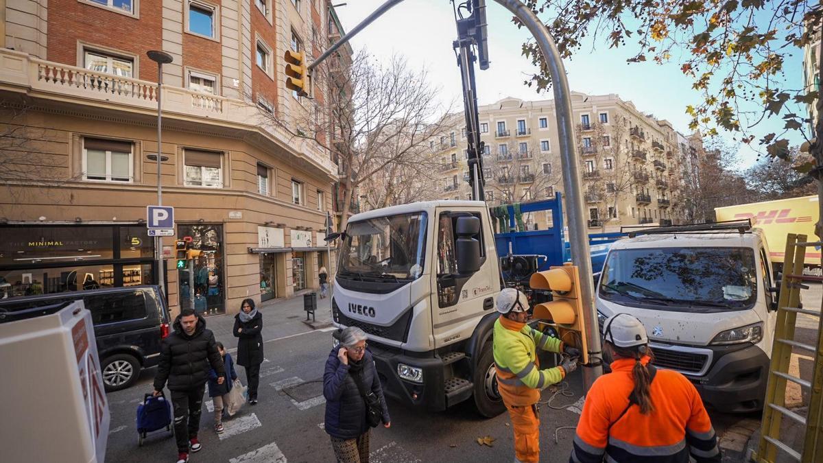 Unos operarios colocan un semáforo en el cruce de Rosselló con Calàbria.