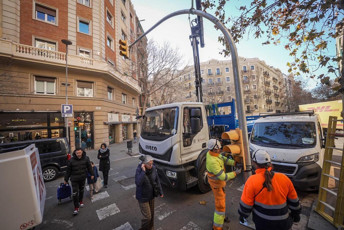 Unos operarios colocan un semáforo en el cruce de Rosselló con Calàbria.