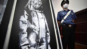 Un policía junto al cuadro de Banksy recuperado en Italia.