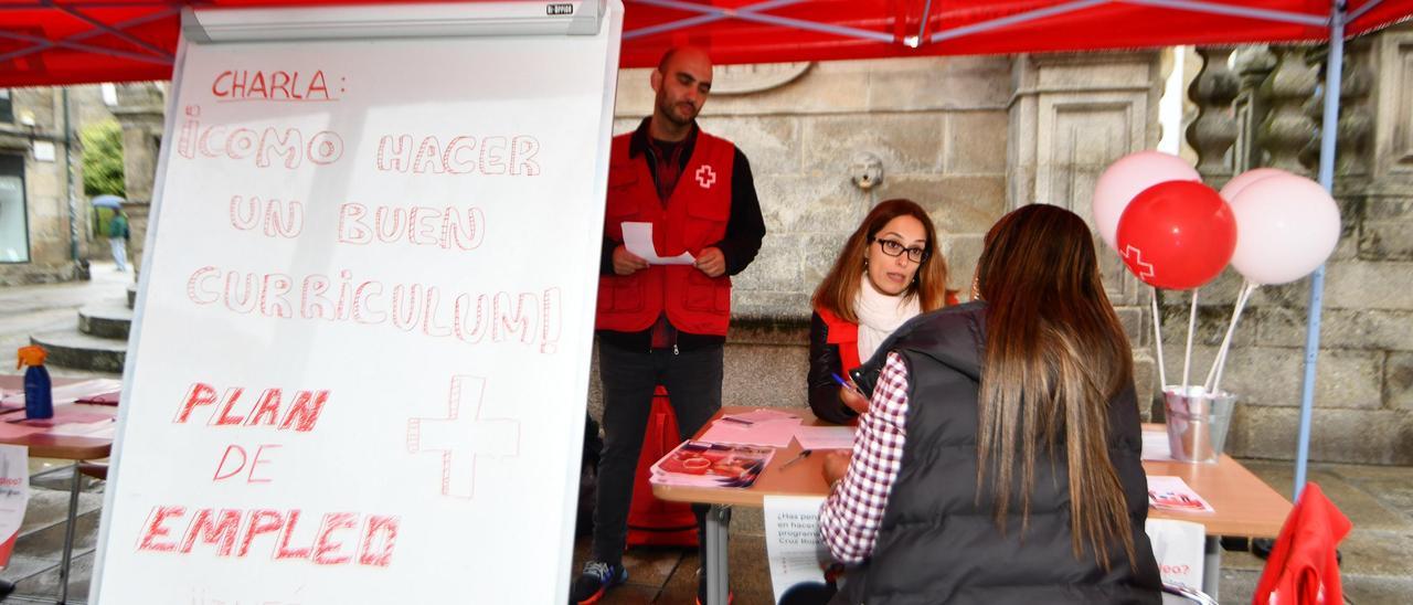 Una mujer se interesa por le Plan de Empleo de Cruz Roja en una de las mesas informativas en A Peregrina.