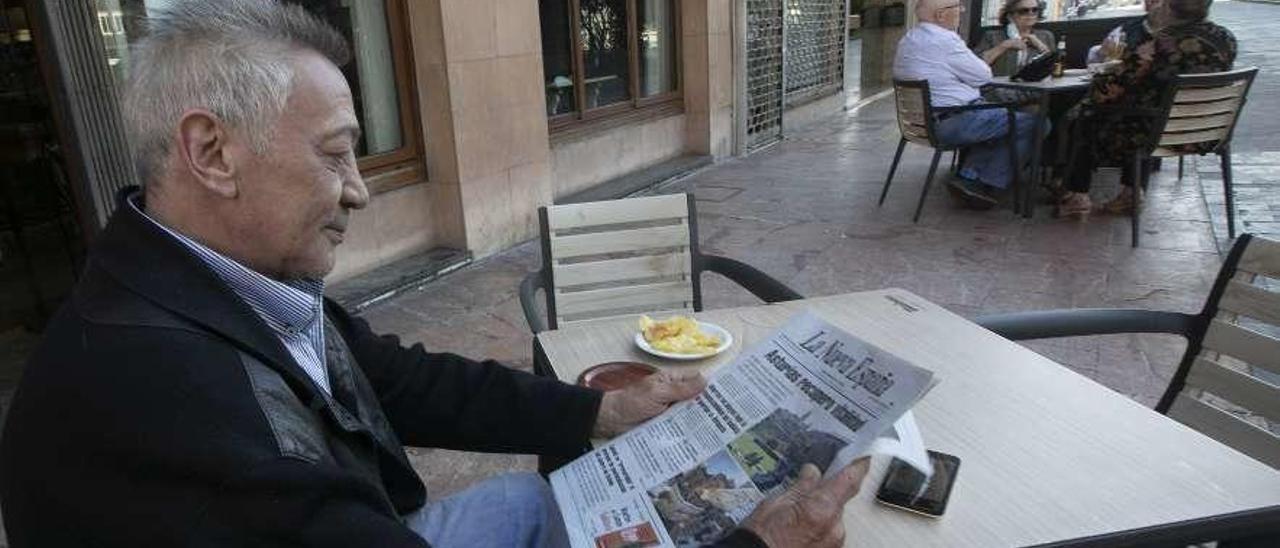 Un cliente lee LA NUEVA ESPAÑA en un bar de la plaza del Fresno de Oviedo.