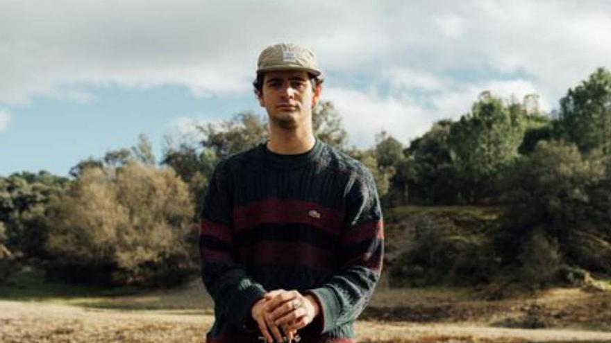 El joven artista navarro posa con su guitarra en la orilla de un río.