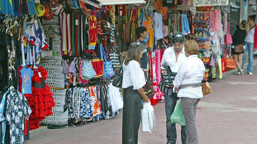 Uns turistes miren les compres que han fet a Lloret, en botigues on es veuen barrets mexicans i sevillanes.