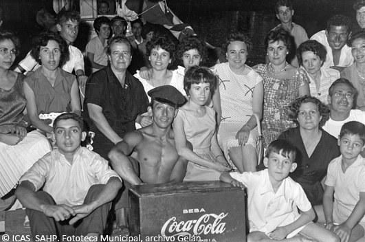 Familia y amigos se reúnen en torno a una nevera de bebida refrescante en una barcaza durante las competiciones en el río. (1969)