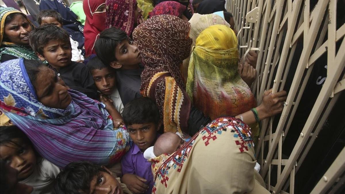 Familias paquistanís esperan en la entrada de un hospital para realizarse las pruebas de VIH.