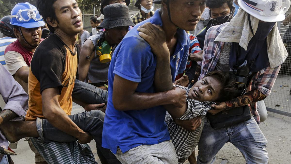 Varios hombres trasladan a un herido en las protestas contra el golpe militar, este domingo en Yangón.