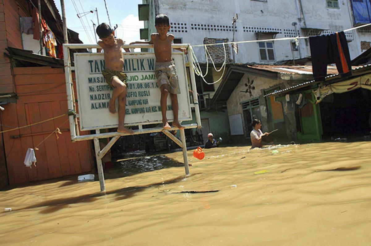 Dos nens indonesis s’agafen a un cartell en una zona residencial de Sumatra, on centenars de vivendes s’han vist afectades per les inundacions causades per fortes pluges. Dos nens indonesis s’agafen a un cartell en una zona residencial de Sumatra, on centenars de vivendes s’han vist afectades per les inundacions causades per fortes pluges.