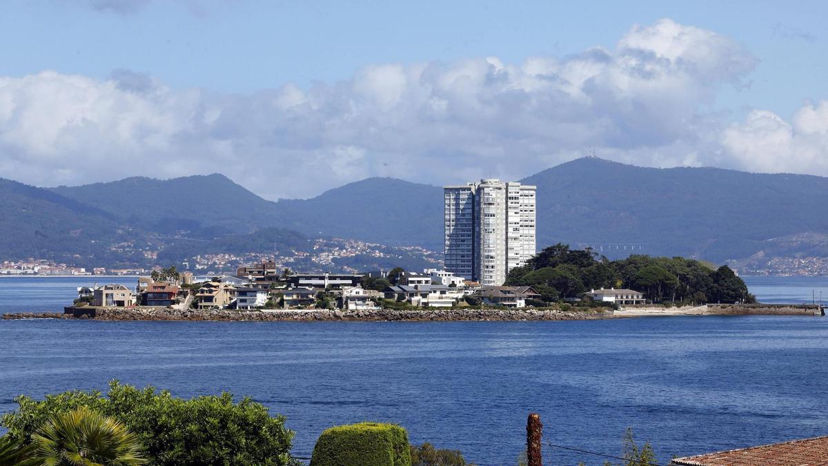 Vista general de la isla de Toralla, en Vigo, a pie de costa, con la torre de viviendas rodeada de casas.