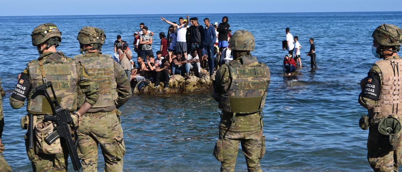 Inmigrantes y militares en la costa de Ceuta.