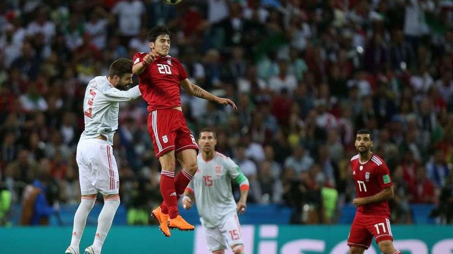 El iraní Azmoun se anticipa a Piqué, con Sergio Ramos al fondo.