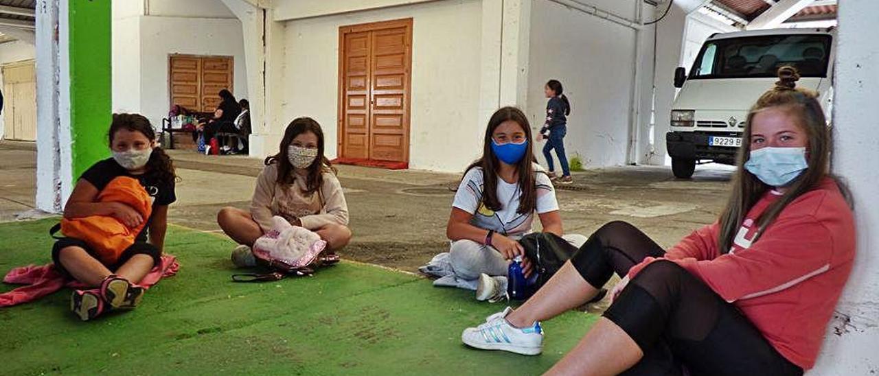 Por la izquierda, Lucía Álvarez, Carmen Feito, Lara Menéndez y Daniela de la Cera, durante un descanso. En la imagen de la derecha, los participantes en el campamento juegan a la quema.