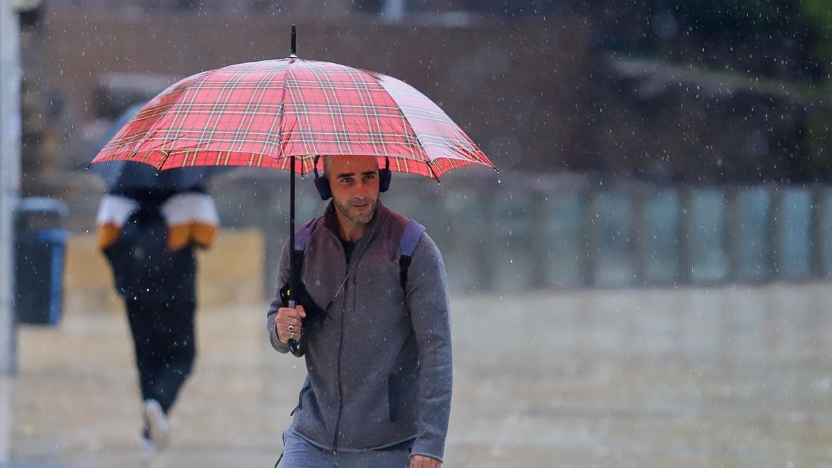 Un hombre pasea bajo la lluvia.