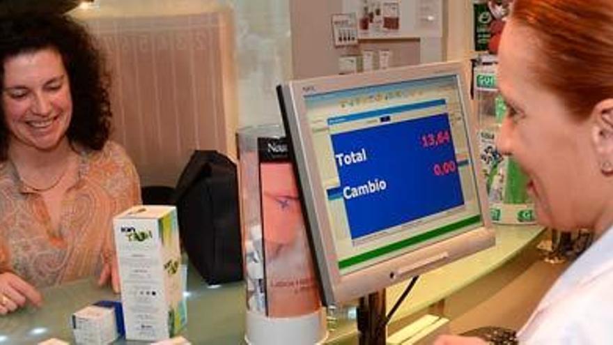 Una clienta recoge sus medicamentos en una farmacia. / RAFA VÁZQUEZ