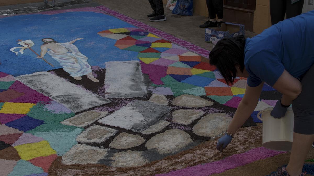 Una voluntaria coloca el serrín de corcho coloreado en las calles de San Vicente.