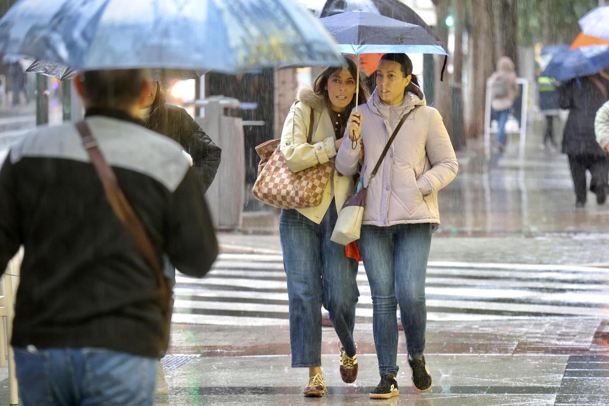 Viandantes bajo la lluvia en Murcia.