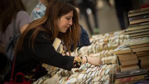 Una mujer busca un libro en el día de Sant Jordi.