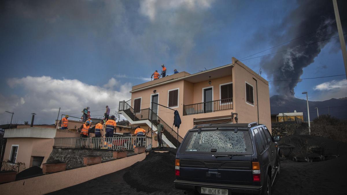 Varios voluntarios retiran ceniza en casas próximas al volcán de La Palma.