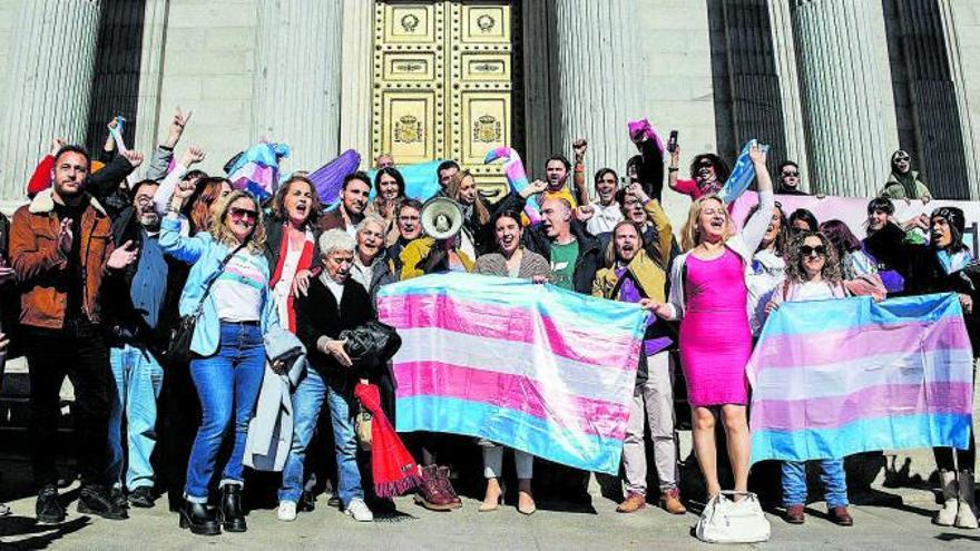 La ministra Irene Montero (centro) y activistas celebran la nueva ley con la bandera trans frente al Congreso de los Diputados.   | // ALEJANDRO MARTÍNEZ