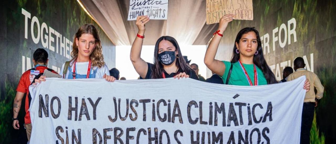 Tres jóvenes activistas se manifiestan durante la cumbre del clima de Sharm el-Sheikh.