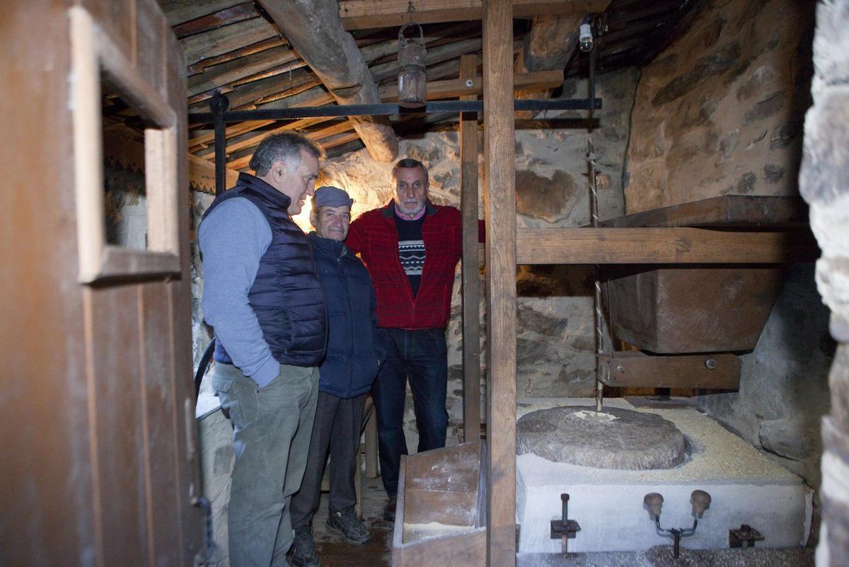 Olegario González, de rojo, en el molino restaurado en El Navaliegu (Laviana).