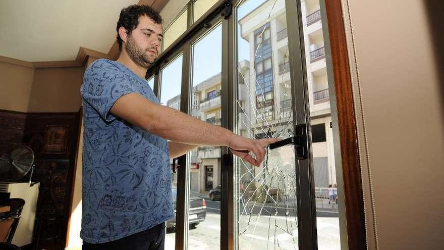 Álvaro Nogueira señala el ventanal por donde entraron a robarle en su local. // Bernabé/Javier Lalín