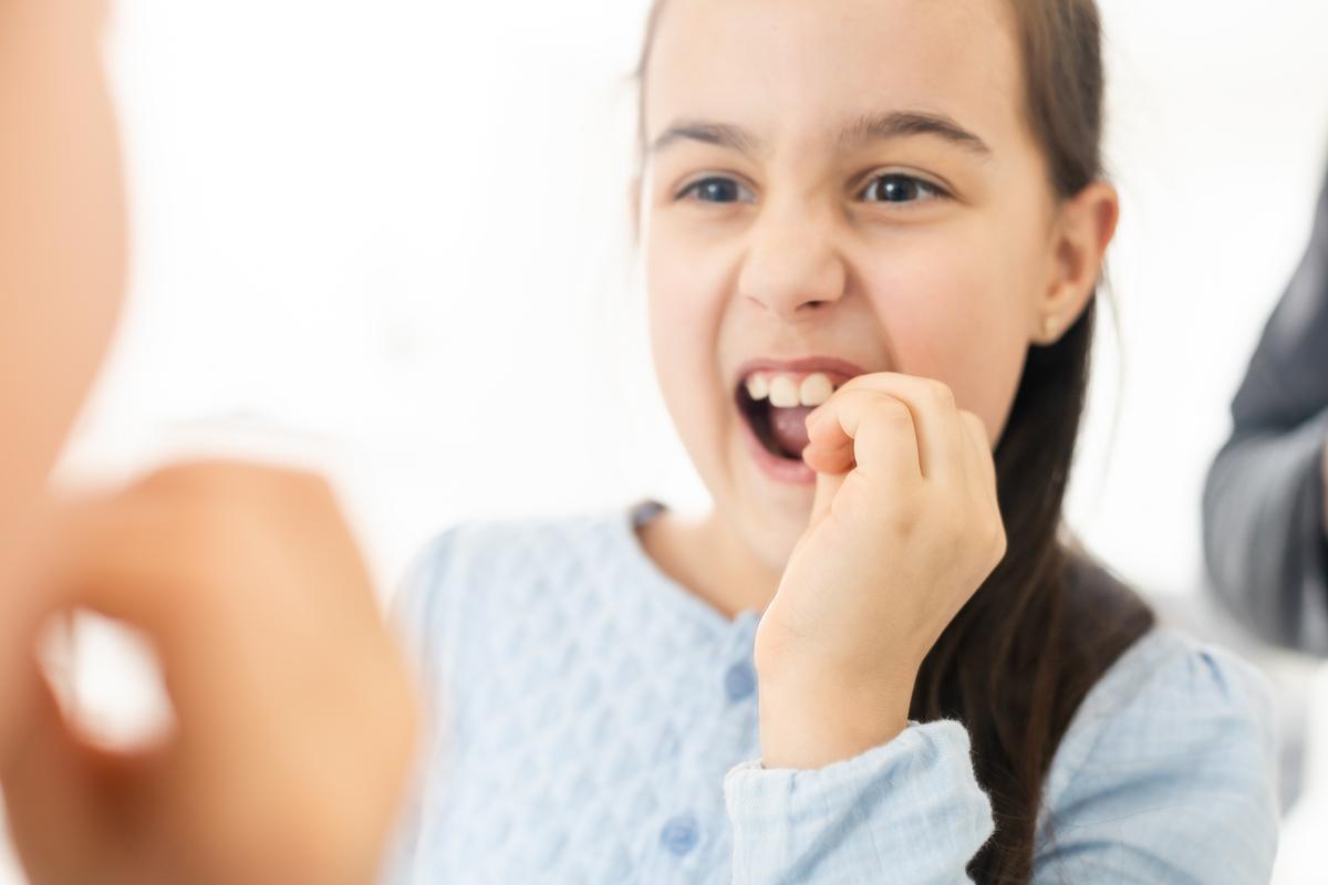 Cute young child holding her tooth which may be loose or aching