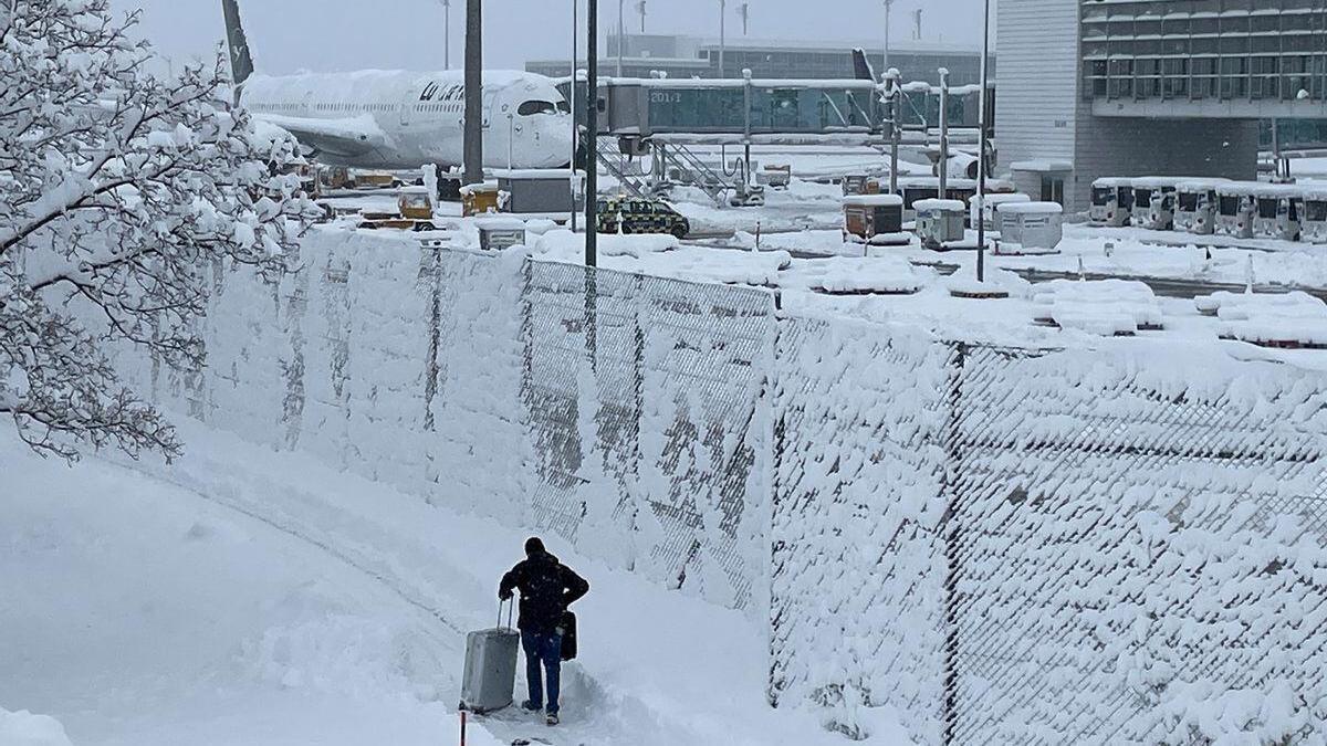 Una persona con su maleta en el aeropuerto de Múnich totalmente nevado.