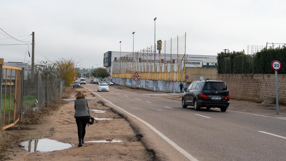 Una persona se dirige hacia el final de la avenida por el camino de tierra lleno de charcos.