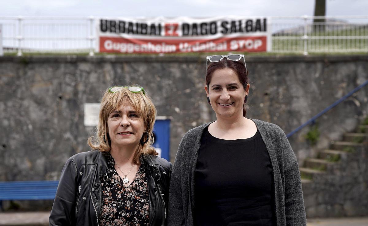 Sorne Rubio, alcaldesa de Mundaca (izq.), junto a Olaia Laka, vicealcaldesa de Ibarrangelu, posan frente a una pancarta contra el proyecto museístico en el puerto de Mundaca.