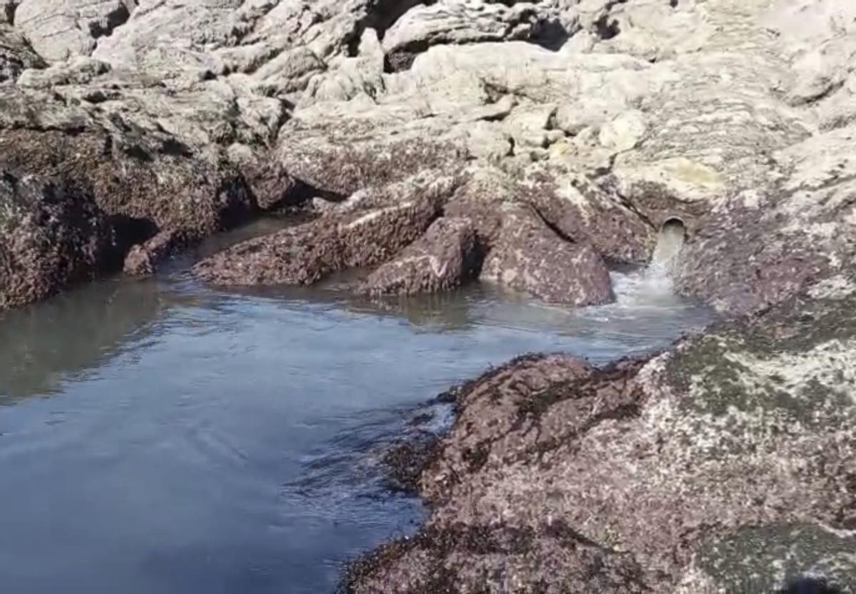 La tubería de alivio en el lugar de O Cantón, «escupiendo» residuos fecales entre las rocas.