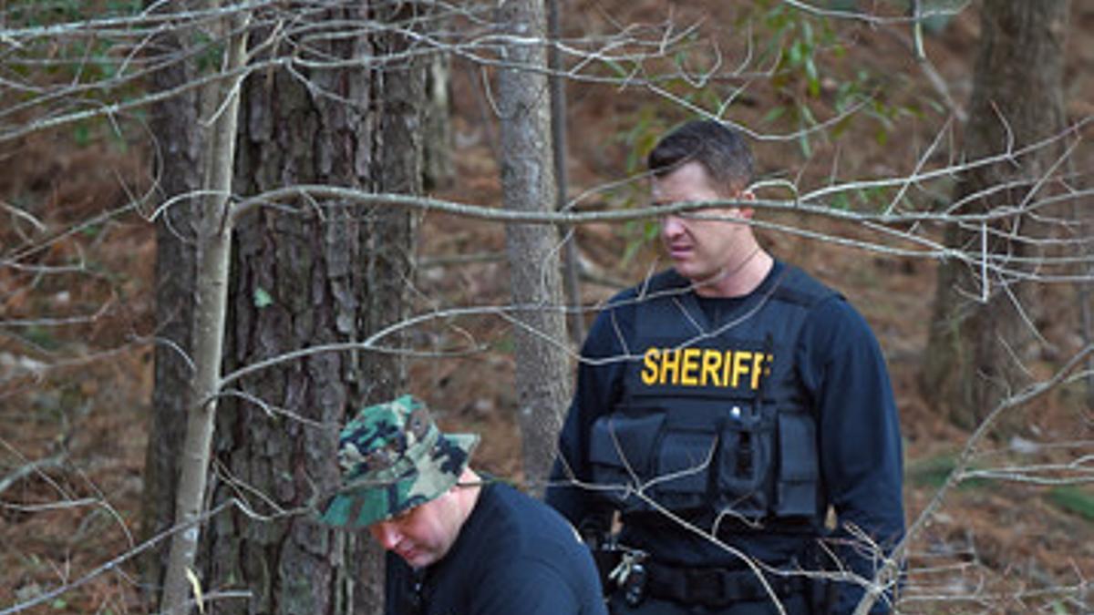 El 'sheriff' Wilson County y dos agentes inspeccionan el terreno cerca de la carretera interestatal en la que se producjo el robo.
