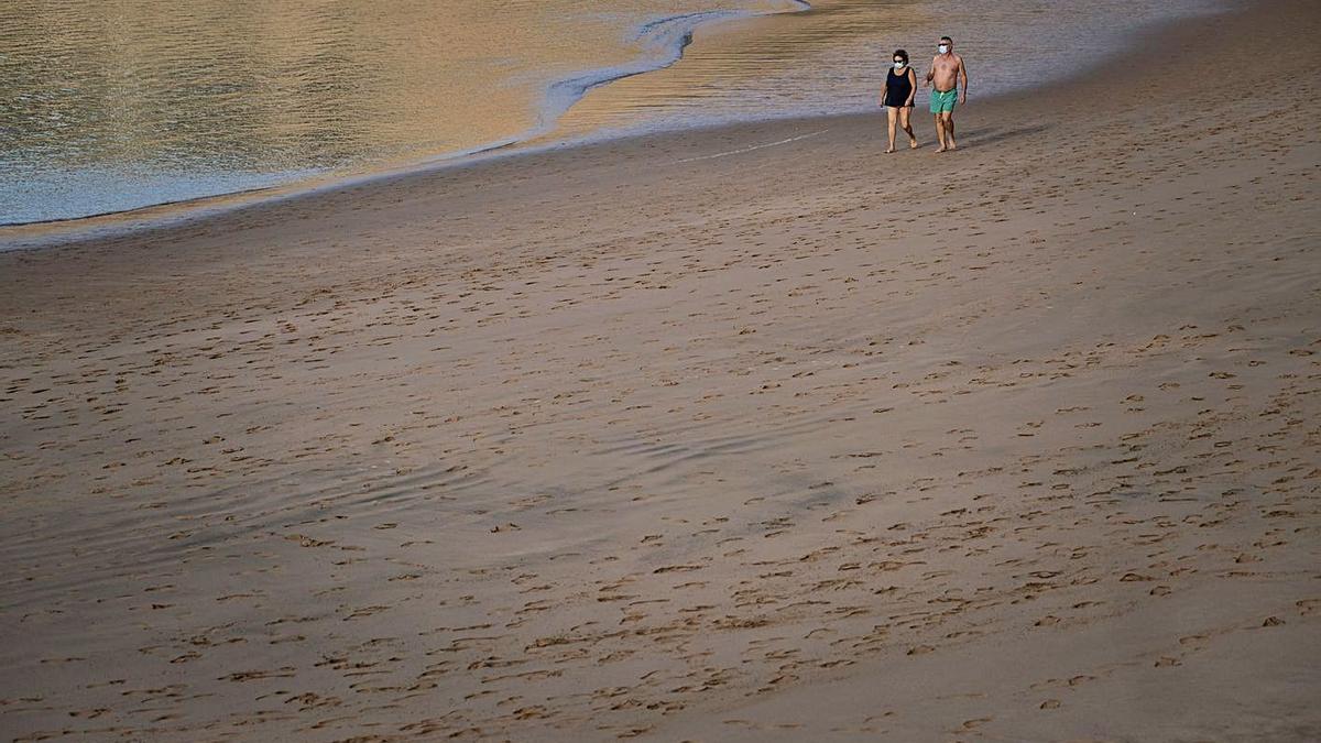 Dos personas pasean por la orilla de la playa de Las Teresitas, en Santa Cruz de Tenerife.