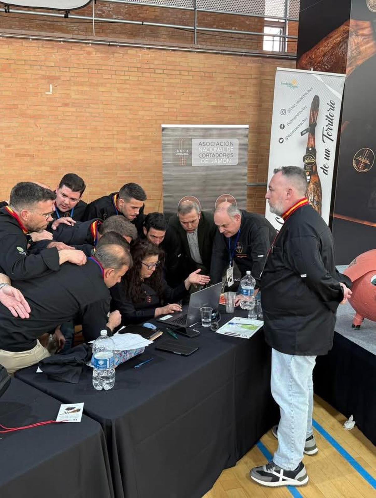Moisés Monroy supervisa a los participantes de la final del Campeonato de España de Cortadores de Jamón, que revisan las puntuaciones.