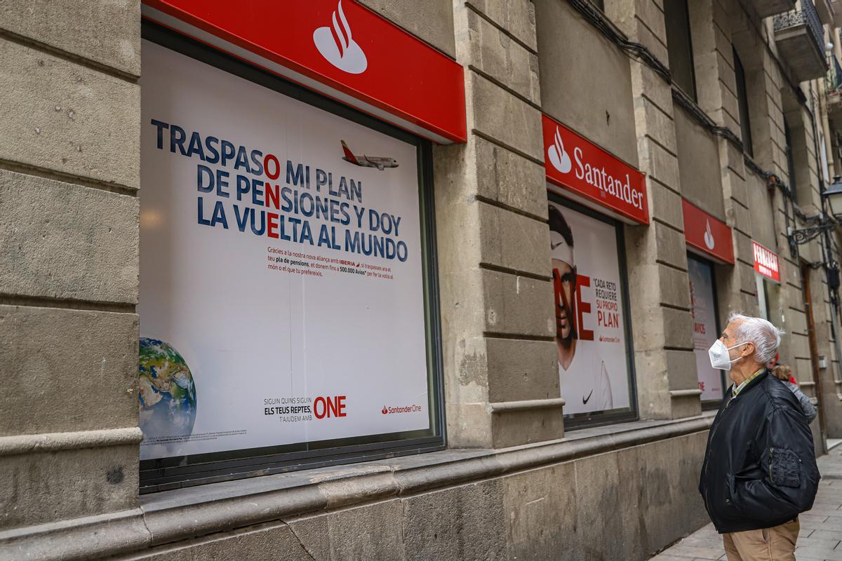 Un hombre observa un anuncio sobre planes de pensiones en una oficina del Santander.