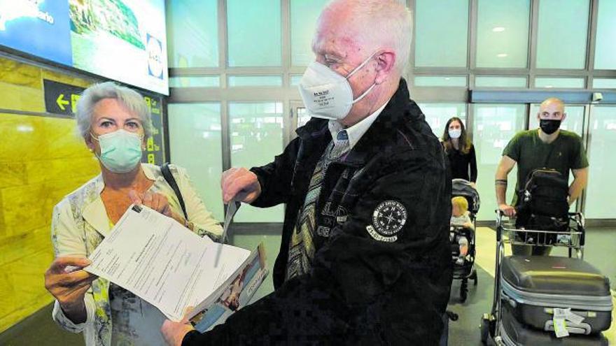 Una pareja de turistas extranjeros muestra el certificado con el resultado de la prueba para detectar el virus a su llegada al aeropuerto.