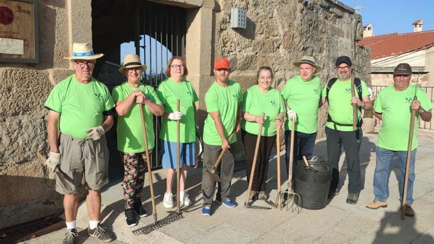 Voluntarios que han participado en la jornada de limpieza del paraje de San Lorenzo y a la derecha la cruz | Cedidas