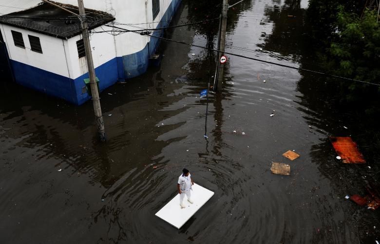 Un treballador utilitza una taula per moure's per un carrer inundat després de fortes pluges a Sao Paulo, Brasil, el passat 7 d'abril.