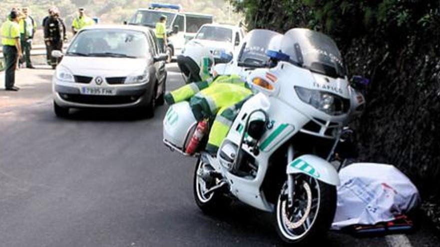 El cadáver del fallecido, cubierto por una sábana, junto a una motocicleta de la Guardia Civil de Tráfico.