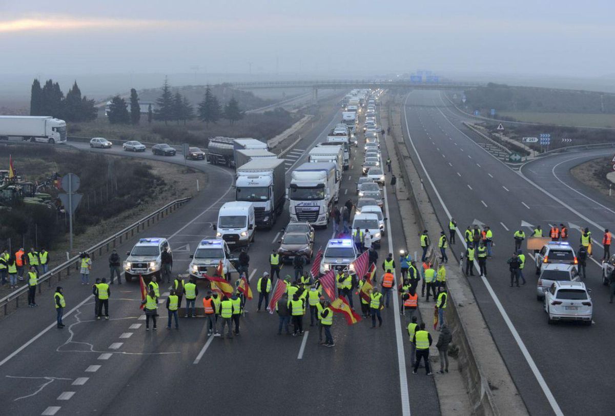 1. «Nuestra ruina hoy, vuestra hambre mañana», una de las pancartas improvisadas para la protesta. 2. Un matrimonio se dirige con su tractor hacia la zona de la concentración. 3. Un helicóptero de la Guardia Civil sobrevolando la zona de la autovía donde se produjeron los tres bloqueos del tráfico. 4. Grupos de agricultores y ganaderos ocupando los carriles de la autovía A-6. | J. A. G.